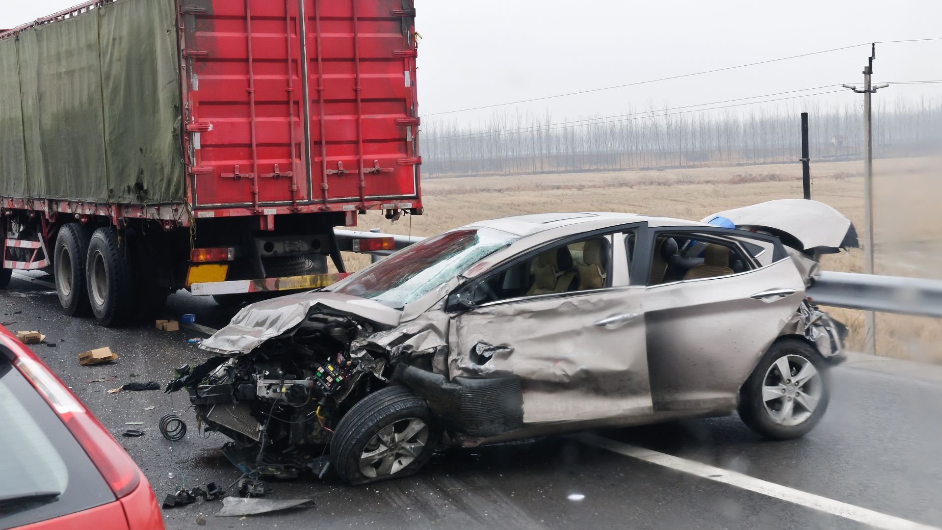 Severely damaged car after collision with large truck on highway