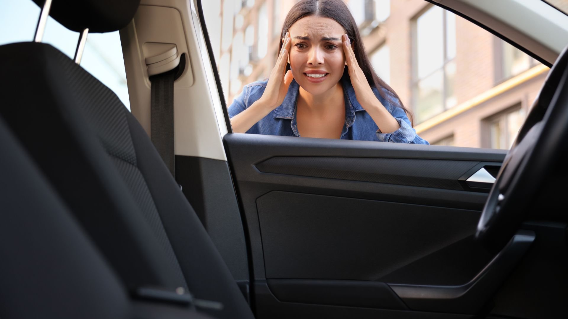 Stressed woman standing by car door with hands on temples