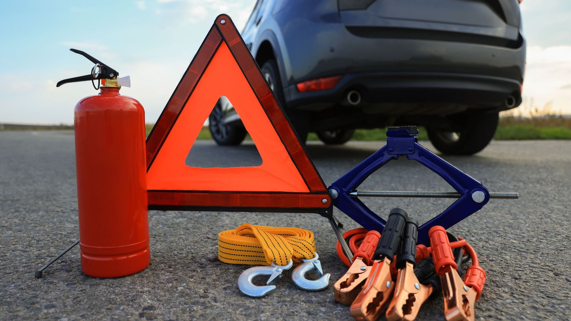 Emergency car kit with warning triangle, fire extinguisher, jumper cables, and tow rope